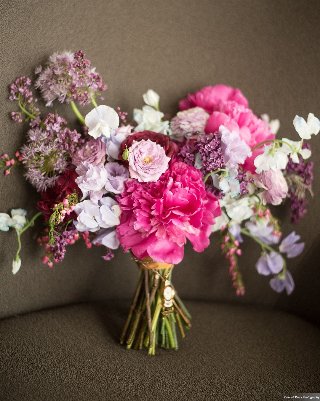 Bright and whimsical bridal bouquet with berry tone flowers featuring peonies, ranunculus, sweet pea and lilac. Nashville wedding florist at Gaylord Opryland.