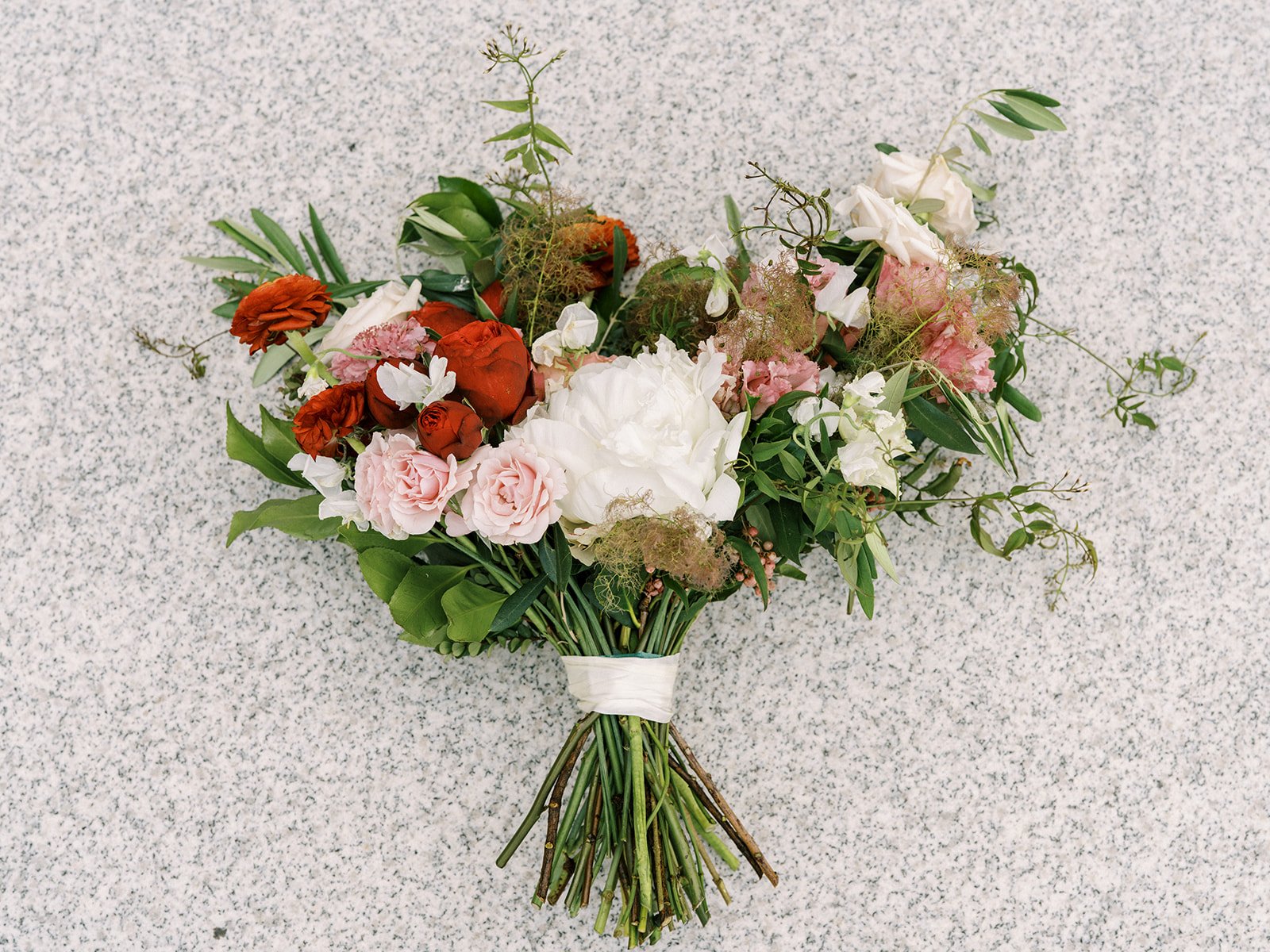 A midsummer nights dream bridal bouquet filled with ranunculus, peonies, garden roses, sweet pea and jasmine vine. Designed by Rosemary and Finch in Nashville, TN.