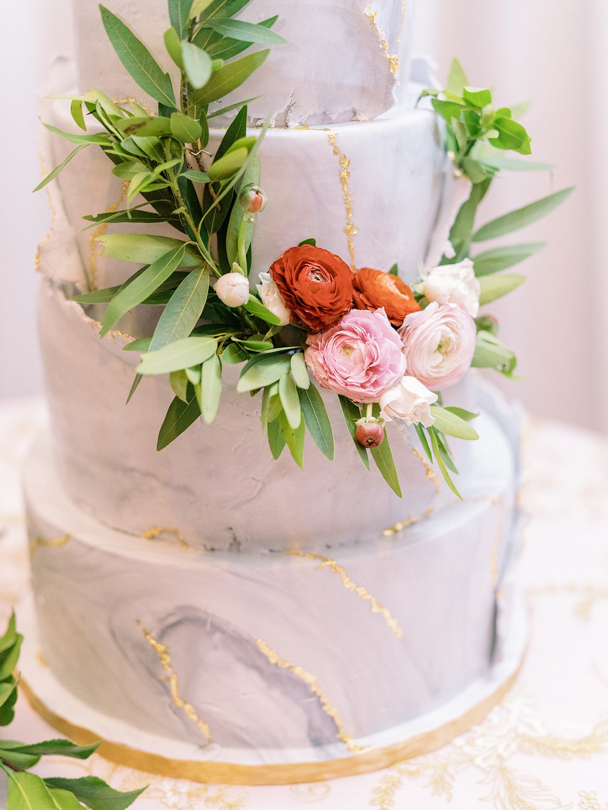 Gorgeous cake florals designed with ranunculus and greenery. Nashville wedding florist at War Memorial.