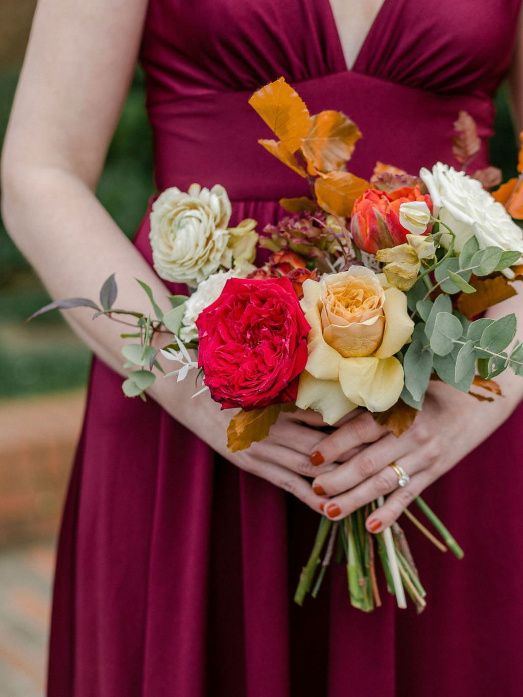 Whimsical bridal party florals featuring vibrant reds, terra cotta, dusty rose, cream, and sage green florals. Fall arrangements highlighted by garden roses, tulips, fall branches, dried hydrangea, and eucalyptus.  Floral design by Rosemary and Finch