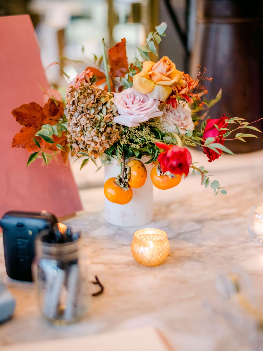 Dainty bud vases of tulips, ranunculus, and fall foliage accenting the reception space. Buds offering pops of warm color and elegance to the smaller spaces of the St. Cecilia restaurant. Floral design by Rosemary and Finch in Nashville, TN.