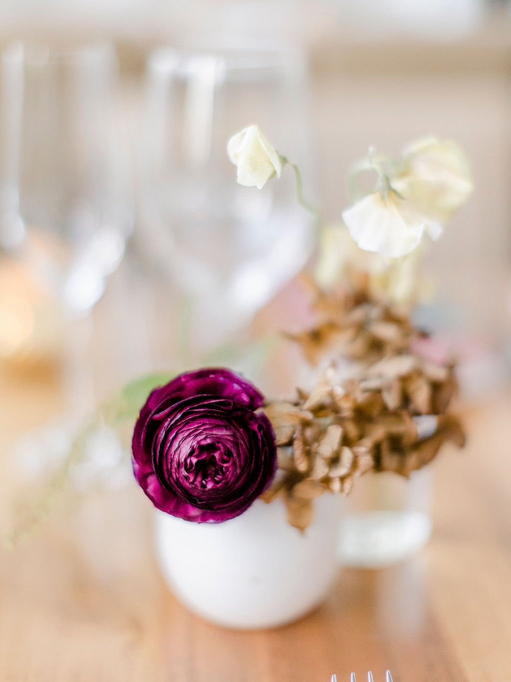 Dainty bud vases of tulips, ranunculus, and fall foliage accenting the reception space. Buds offering pops of warm color and elegance to the smaller spaces of the St. Cecilia restaurant. Floral design by Rosemary and Finch in Nashville, TN.