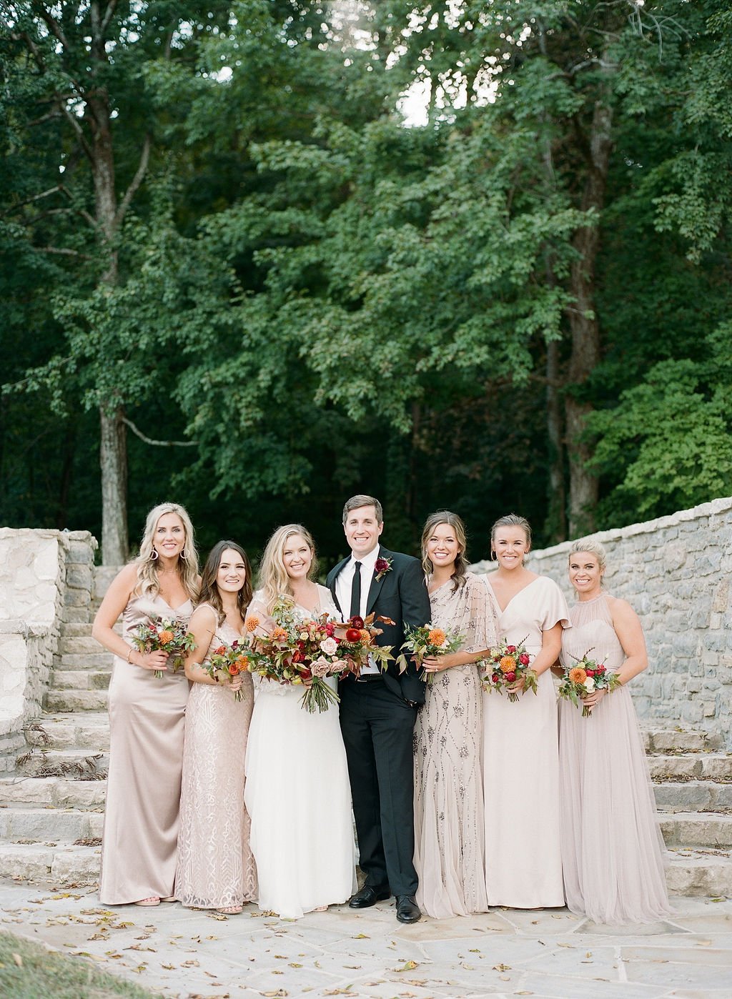 Sweet bridesmaid bouquet comprised of greenery, burnt orange, cream and pops of burgundy flowers featuring ranunculus, garden roses and dahlias. Floral Design by Rosemary and Finch in Nashville, TN.