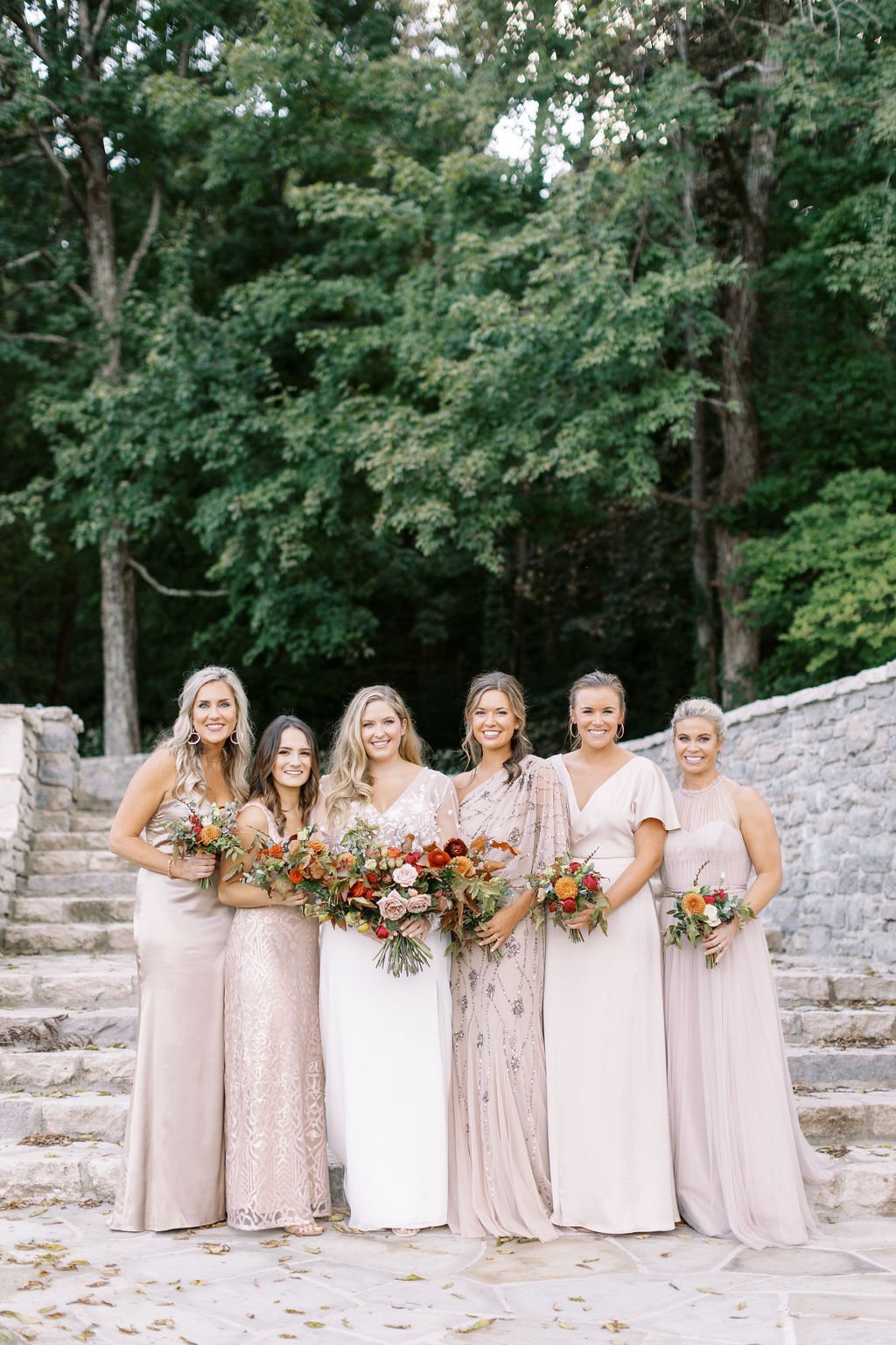 Sweet bridesmaid bouquet comprised of greenery, burnt orange, cream and pops of burgundy flowers featuring ranunculus, garden roses and dahlias. Floral Design by Rosemary and Finch in Nashville, TN.