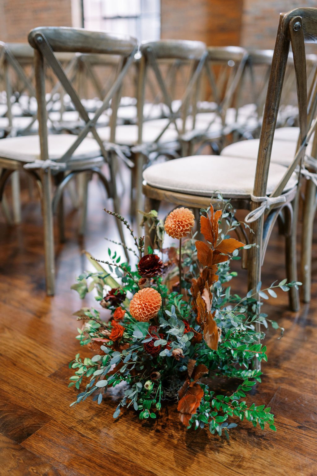 Organic ceremony aisle markers accompanied the installations with pops of burgundy, burnt orange, terra cotta, cream and fall foliage. Florals include garden roses, ranunculus, and dahlias. Floral Design by Rosemary and Finch in Nashville, TN.