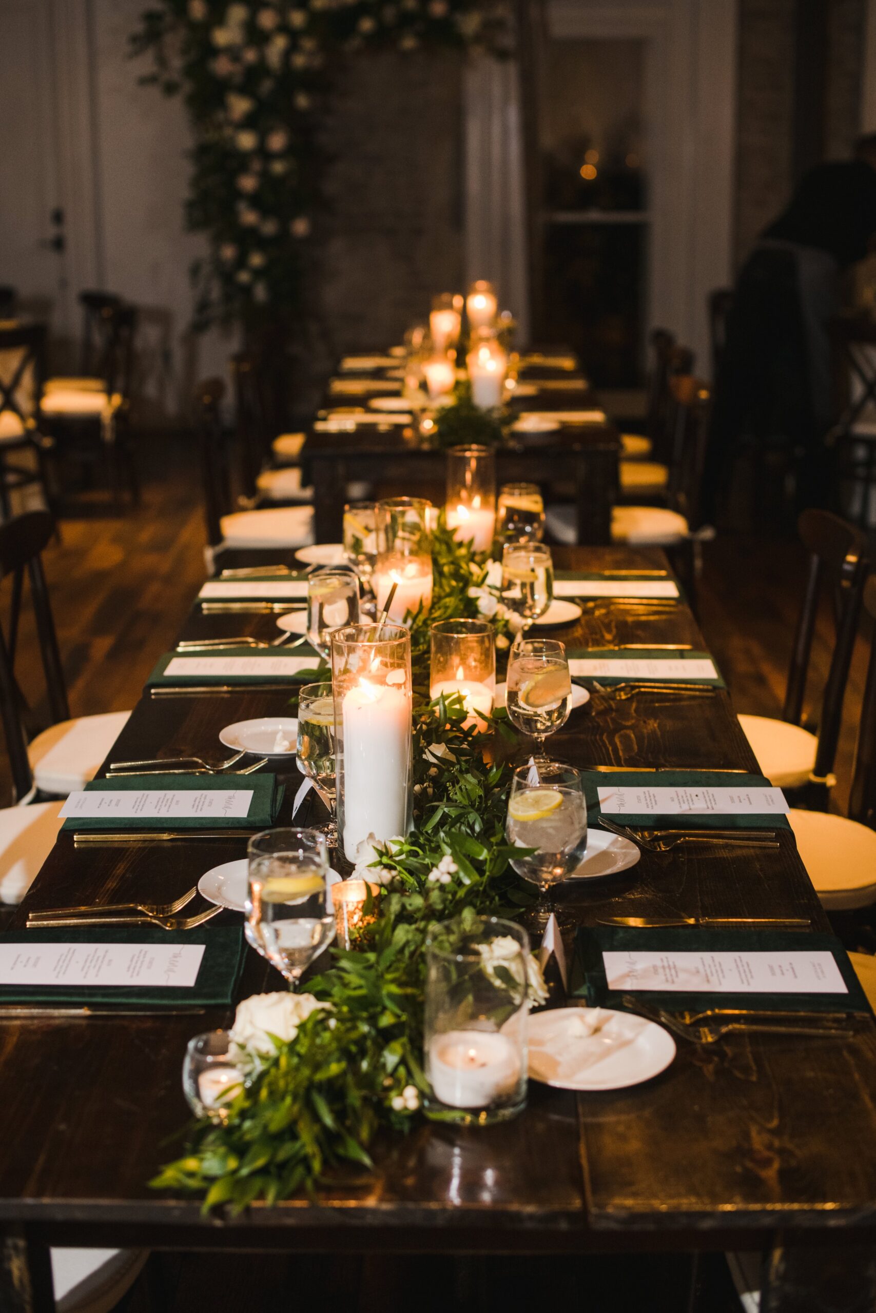 Elegant tablescapes for garden-inspired white and green wedding. Dark green tapers and natural garland. Accented with gold votives and petal heavy white roses. Designed by Rosemary and Finch in Nashville, TN.