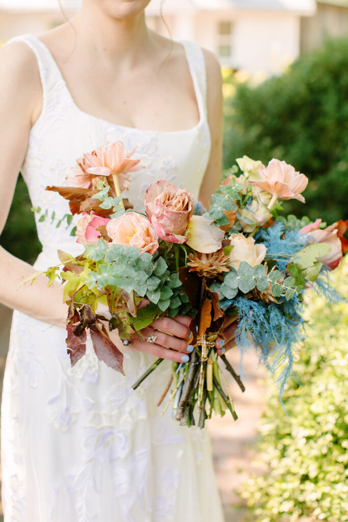 An artful fall bridal bouquet of petal heavy tulips, ranunculus, and garden roses in varying hues of mustard yellow, terra cotta, and dusty rose. Featuring ferns and eucalyptus. Design by Rosemary and Finch in Nashville, TN.