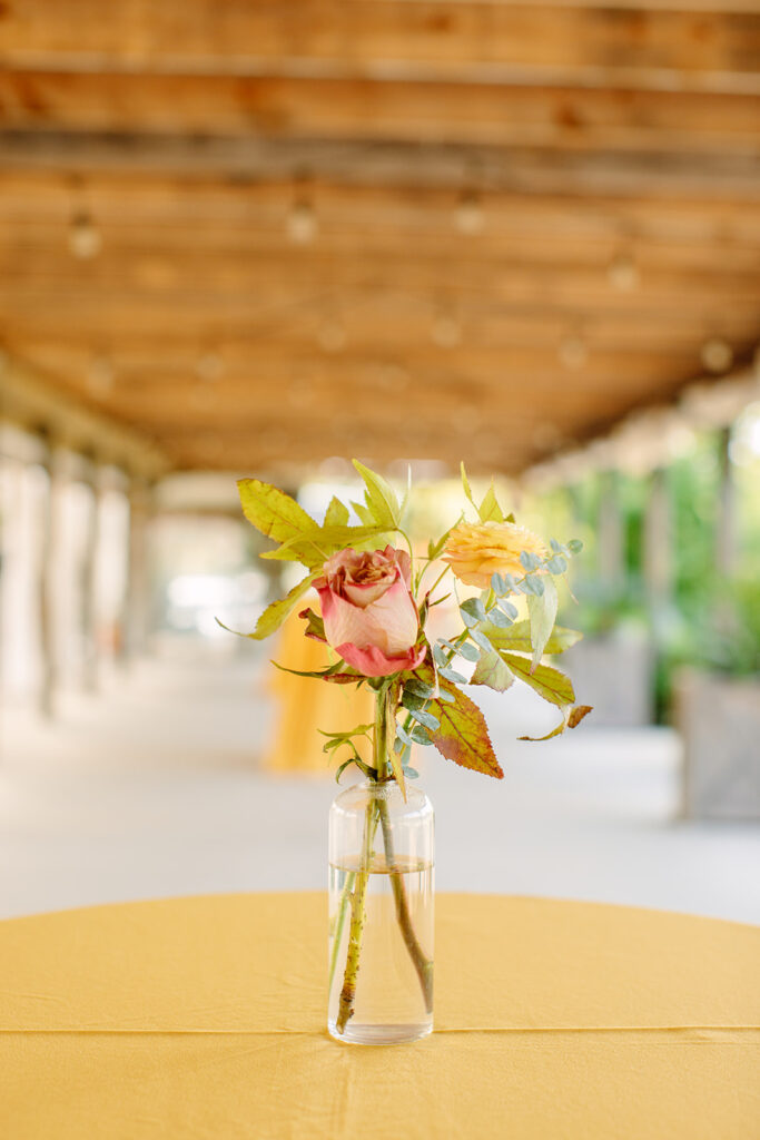 Whimsical bud vases accent the reception space with dusty rose, mustard yellow, and sage green hues. Florals comprised of roses, ranunculus, eucalyptus, and fall foliage. Designed by Rosemary and Finch in Nashville, TN.
