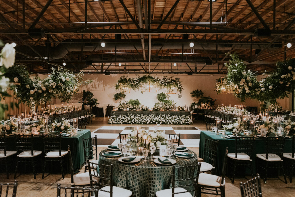 Organic growing chandelier floral installations and floral meadows fill this wedding reception with petal heavy roses, ranunculus, panda anemones, lisianthus, delphinium, and dark greenery in hues of white, cream, black and emerald. Designed by Rosemary and Finch in Nashville, TN. 