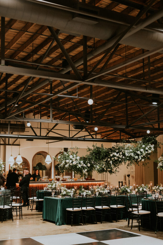 Eye-catching hanging floral installation decorate this winter wedding reception tables with floral hues of white, cream, black, and emerald composed of petal heavy roses, anemones, delphinium, carnations, and natural greenery. Design by Rosemary and Finch in Nashville, TN.