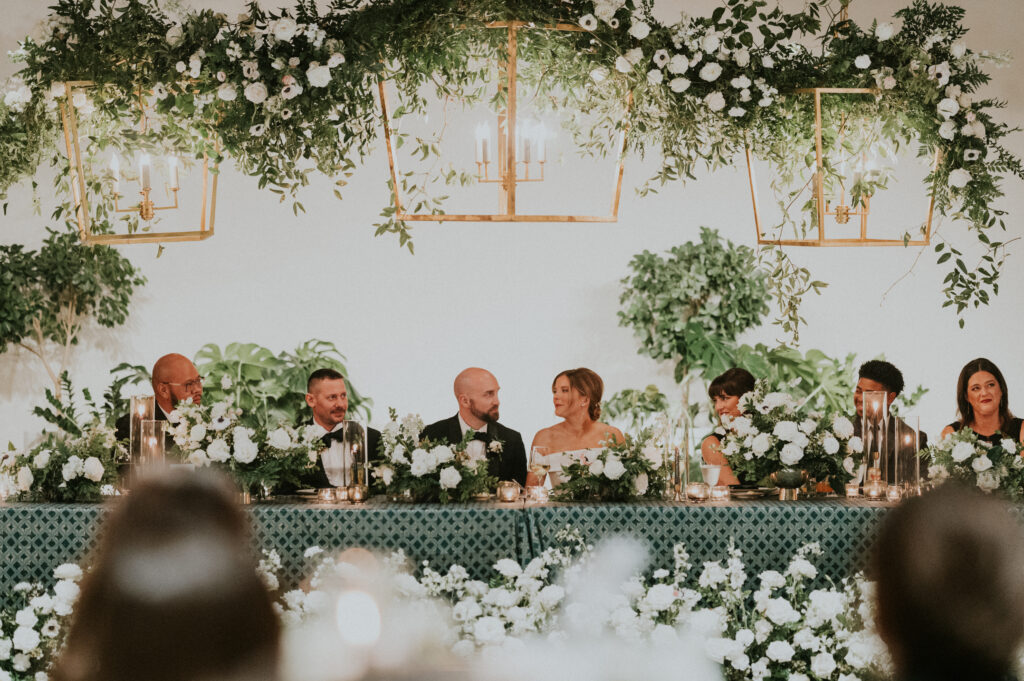Organic growing chandelier floral installations and floral meadows fill this wedding reception with petal heavy roses, ranunculus, panda anemones, lisianthus, delphinium, and dark greenery in hues of white, cream, black and emerald. Designed by Rosemary and Finch in Nashville, TN. 
