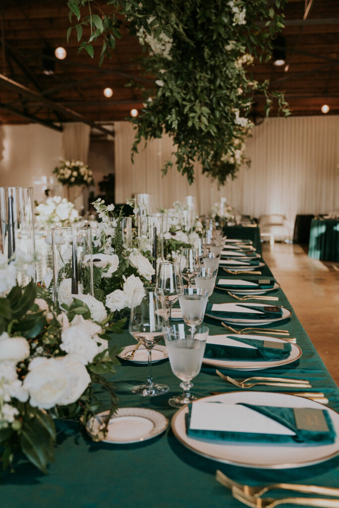 Low floral centerpieces for elegant wedding overflow with white garden roses, ranunculus, scabiosa, lisianthus, sweet peas, delphinium, and natural dark greenery. Floral hues of white, cream, and emerald. Designed by Rosemary and Finch in Nashville, TN.