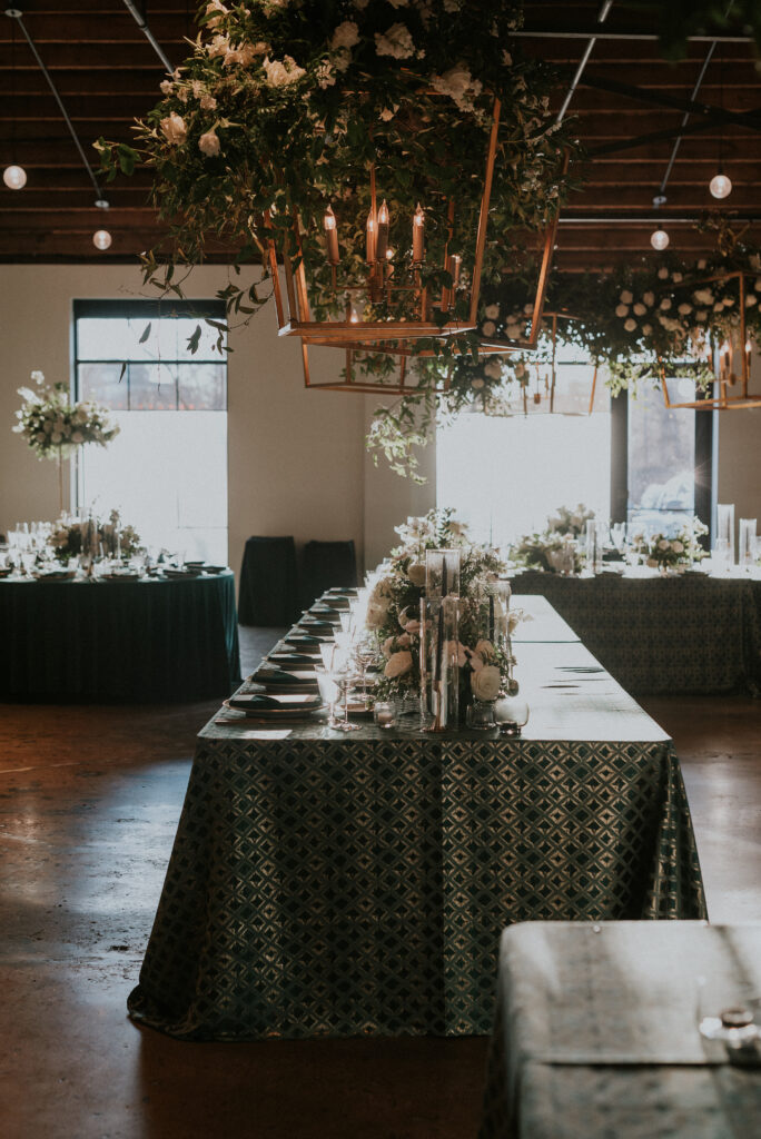 Low floral centerpieces for elegant wedding overflow with white garden roses, ranunculus, scabiosa, lisianthus, sweet peas, delphinium, and natural dark greenery. Floral hues of white, cream, and emerald. Designed by Rosemary and Finch in Nashville, TN.