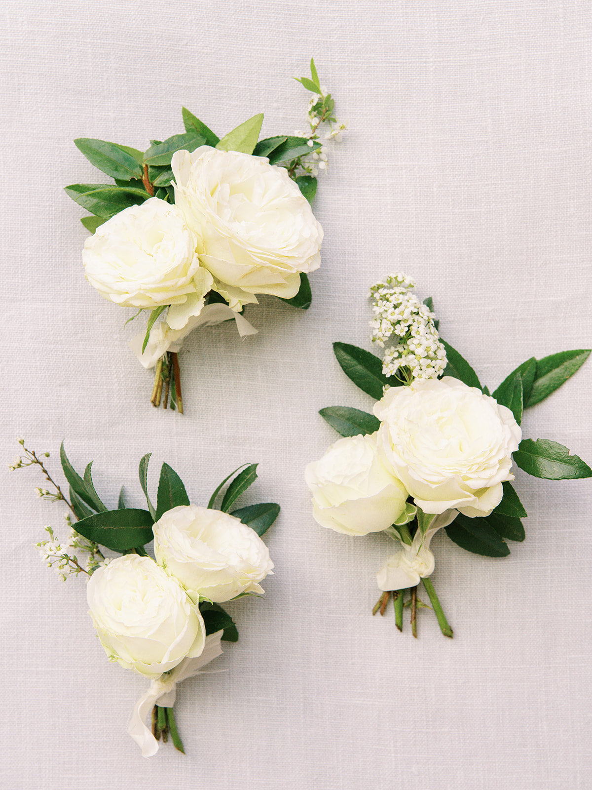 Dainty white classic boutonnieres with white garden spray roses and spirea. Garden inspired Nashville, TN church wedding. Design by Rosemary and Finch Floral Design in Nashville, TN
