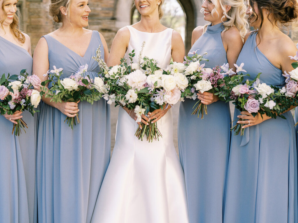 Classic white, green, and lavender garden inspired bridal party bridesmaid’s bouquets with peonies, roses, clematis, spirea, butterfly ranunculus, and ranunculus florals. Spring church wedding large lush bridal bouquet. Design by Rosemary and Finch Floral Design in Nashville, TN.