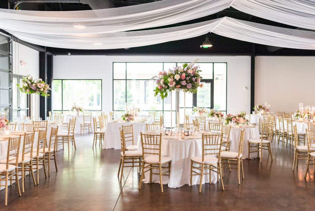 Beautiful summer wedding ceremony and reception elevated centerpieces. Pastel flower colors in light pink, lavender, cream, blush, dusty blue, peach, and natural green consisting of large roses, ranunculus, and delphinium. Design by Rosemary and Finch at Cherokee Dock in Nashville, TN. 