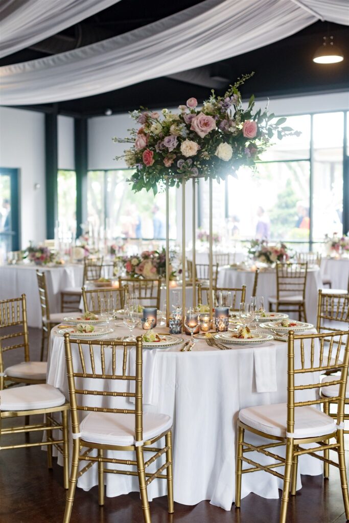 Beautiful summer wedding ceremony and reception elevated centerpieces. Pastel flower colors in light pink, lavender, cream, blush, dusty blue, peach, and natural green consisting of large roses, ranunculus, and delphinium. Design by Rosemary and Finch at Cherokee Dock in Nashville, TN. 