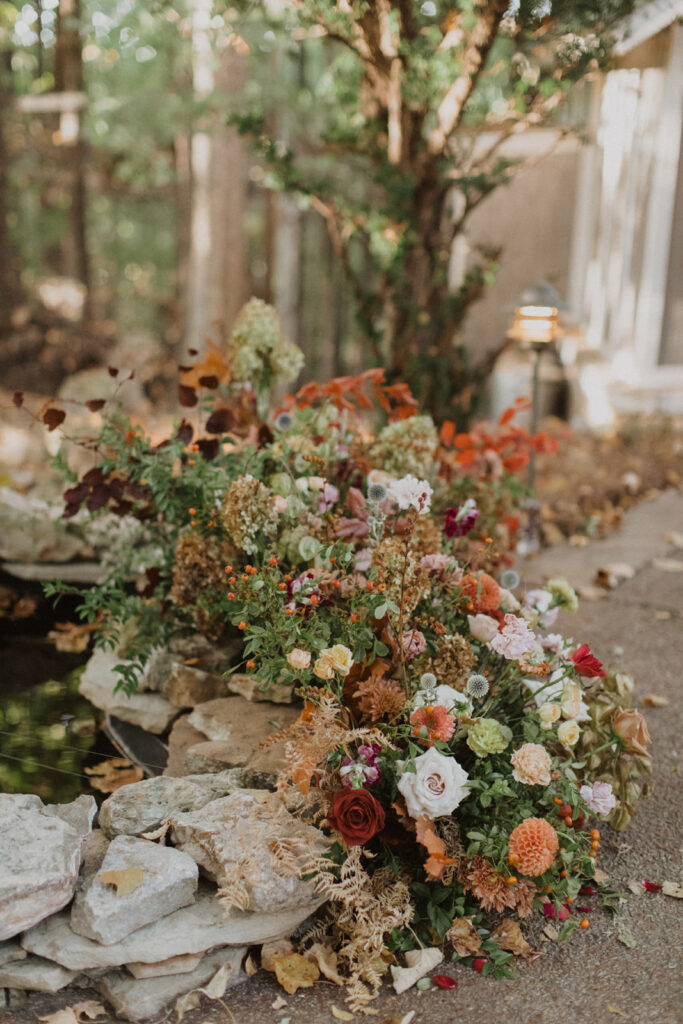 Growing fall wedding ceremony floral meadows in colors of burgundy, plum, copper, pale yellow, terra cotta, cream, dusty pink, and lavender. Hanging flowers and ground floral meadow for intimate fall wedding ceremony. Design by Rosemary and Finch Floral Design in Nashville, TN.