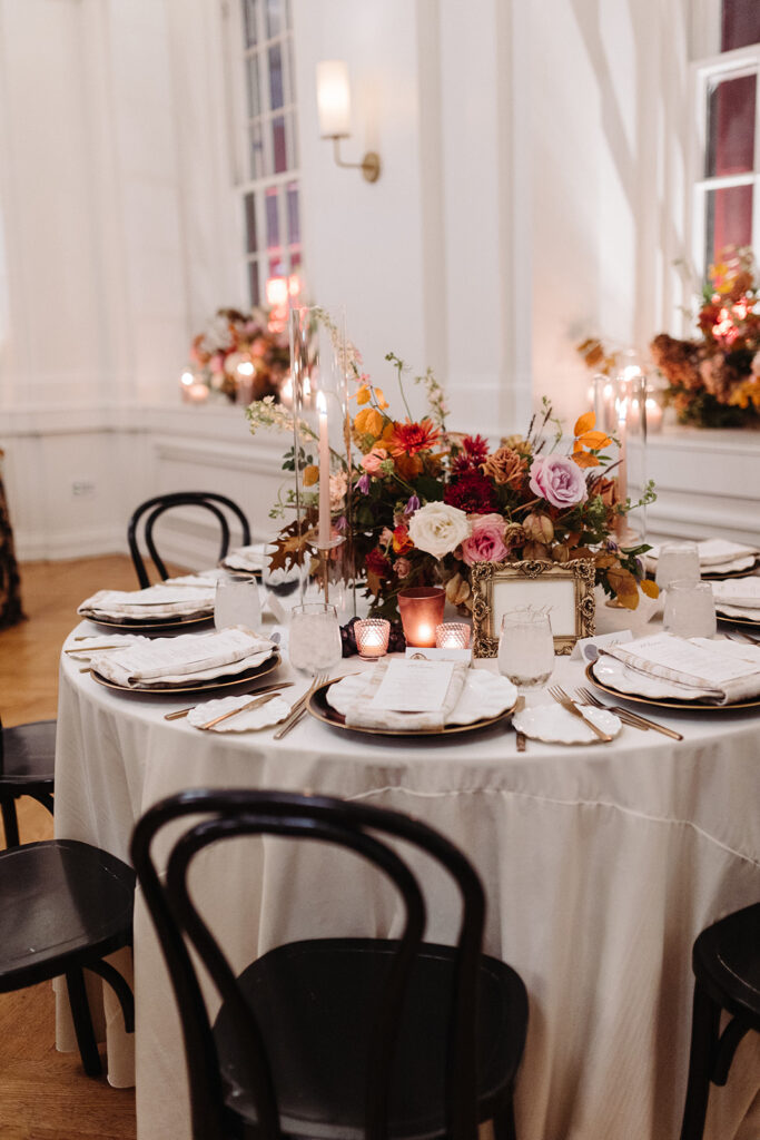 Organic fall floral centerpieces decorate this autumnal Parisian inspired wedding reception in hues of dusty rose, burgundy, terra cotta, and lavender composed of roses, ranunculus, delphinium, lisianthus, copper beech, and fall foliage. Fall wedding in Downtown Nashville. Design by Rosemary & Finch Floral Design in Nashville, TN. 