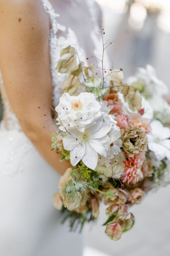 Fall bridal bouquet with lush autumnal colors of mauve, dusty pink, cream, white, peach, taupe, and green. Florals of dahlias, roses, clematis, lisianthus, and natural greenery. Fall wedding in Raleigh, NC. Design by Rosemary and Finch Floral Design in Nashville, TN. 