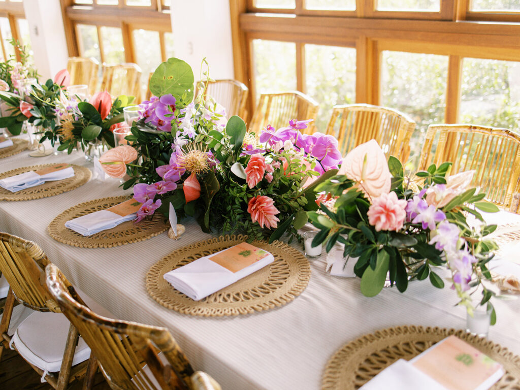 Exuma, Bahamas destination wedding rehearsal dinner tropical floral design. Tropical table floral meadows consisting of orchids, wild ginger, and anthurium in peach, pink, magenta, orange, and green tones. Spring beach wedding floral design by Rosemary & Finch Floral Design. 