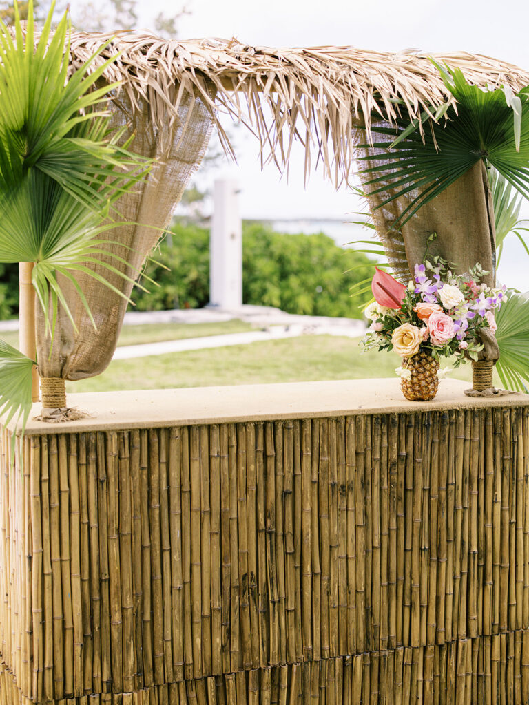 Tropical floral arrangements in pineapples for private estate spring destination beach wedding in Exuma, Bahamas. Orchids and roses in tropical colors of orange, pink, lavender, dusty blue pale yellow and natural greens. Destination floral design by Rosemary & Finch Floral Design.