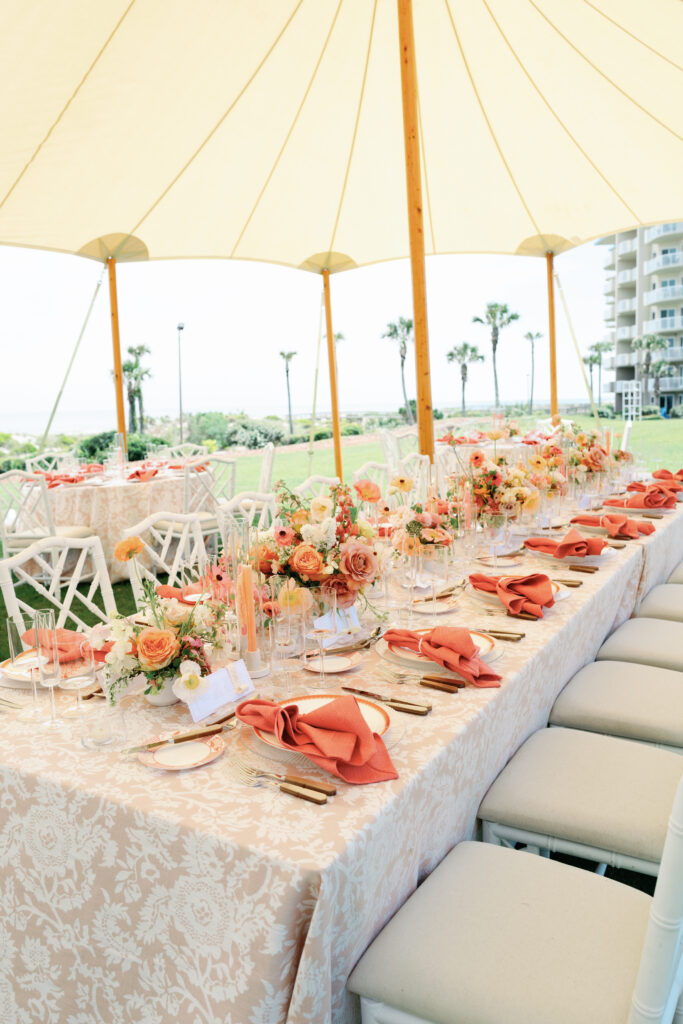 Colorful low centerpieces for beach wedding at The Ritz-Carlton Amelia Island. Wedding reception photoshoot with lush ranunculus, poppies, and dogwood branches. Fun tangerine, peach, blush, coral, orange, and cream floral colors for vibrant spring beach wedding reception. Destination floral design by Rosemary & Finch Floral Design. 