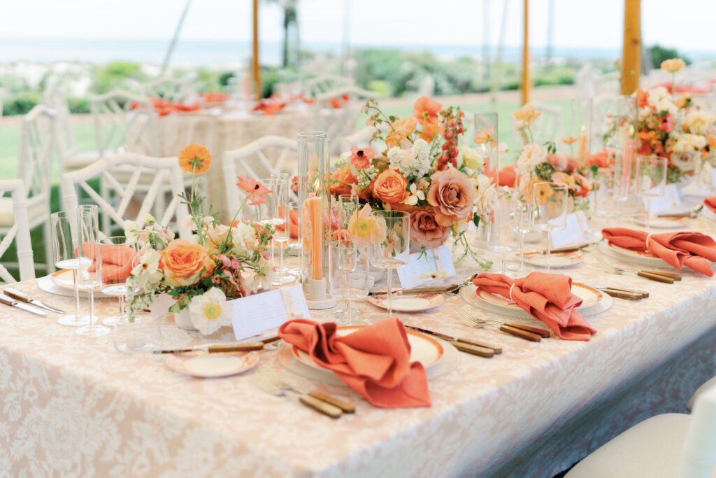 Colorful low centerpieces for beach wedding at The Ritz-Carlton Amelia Island. Wedding reception photoshoot with lush ranunculus, poppies, and dogwood branches. Fun tangerine, peach, blush, coral, orange, and cream floral colors for vibrant spring beach wedding reception. Destination floral design by Rosemary & Finch Floral Design. 
