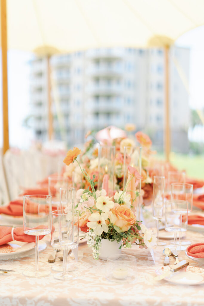 Colorful accent table centerpieces for beach wedding at The Ritz-Carlton Amelia Island. Wedding reception photoshoot with lush ranunculus, poppies, and dogwood branches. Fun colorful candles in pink and coral for spring wedding reception. Fun tangerine, peach, blush, coral, orange, and cream floral colors for vibrant spring beach wedding reception. Destination floral design by Rosemary & Finch Floral Design. 
