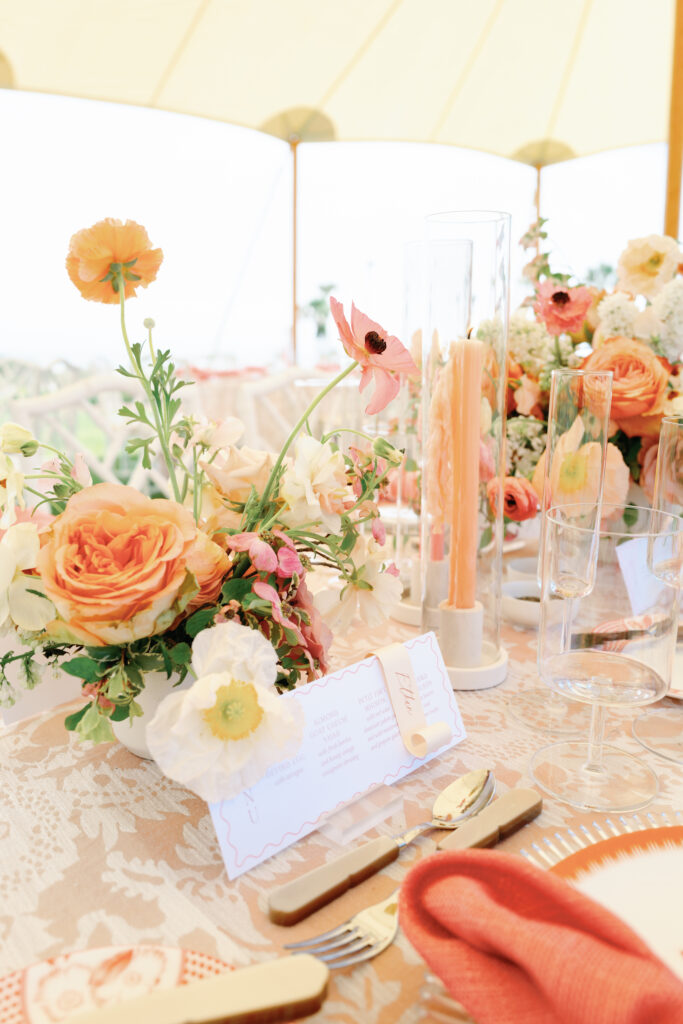 Colorful low centerpieces for beach wedding at The Ritz-Carlton Amelia Island. Wedding reception photoshoot with lush ranunculus, poppies, and dogwood branches. Fun tangerine, peach, blush, coral, orange, and cream floral colors for vibrant spring beach wedding reception. Fun colorful candles in pink and coral for spring wedding reception. Destination floral design by Rosemary & Finch Floral Design. 