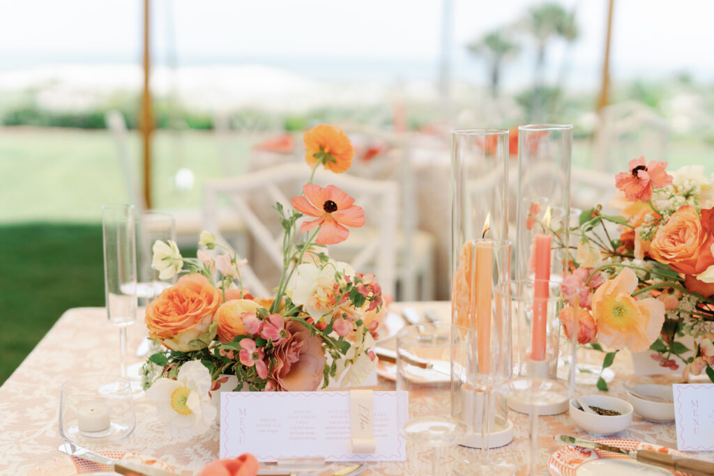 Colorful accent table centerpieces for beach wedding at The Ritz-Carlton Amelia Island. Wedding reception photoshoot with lush ranunculus, poppies, and dogwood branches. Fun colorful candles in pink and coral for spring wedding reception. Fun tangerine, peach, blush, coral, orange, and cream floral colors for vibrant spring beach wedding reception. Destination floral design by Rosemary & Finch Floral Design. 