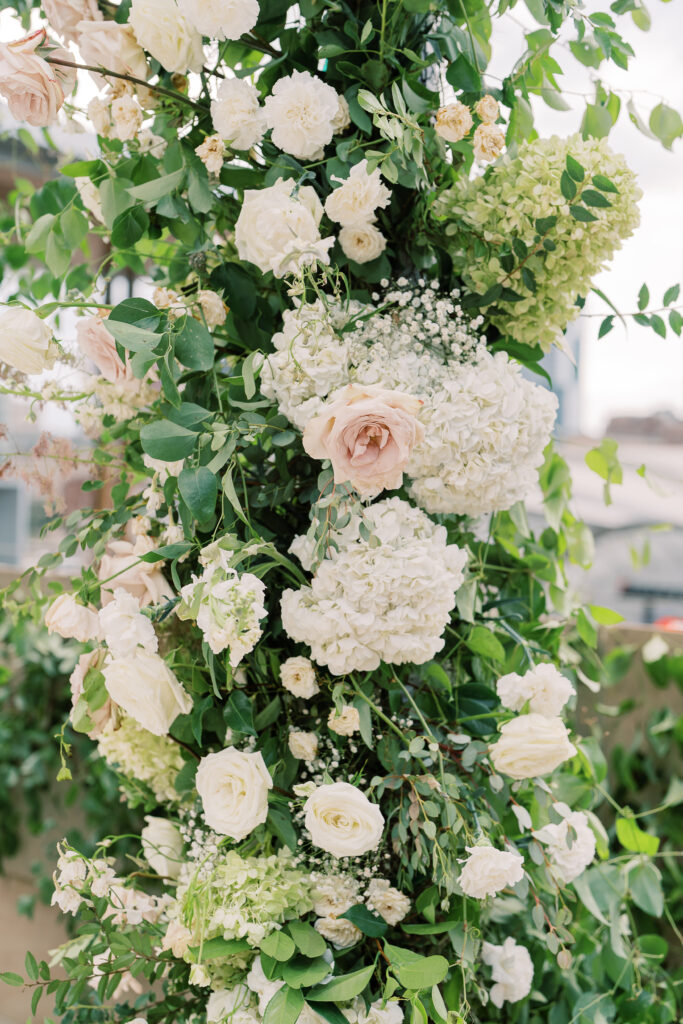 Oversized ceremony floral arch for summer wedding. Classic and timeless floral design in white, cream, taupe, champagne, and green. Lush ceremony florals for garden-inspired summer wedding. Florals composed of roses, hydrangea, baby’s breath, and organic greenery. Design by Rosemary & Finch Floral Design. 