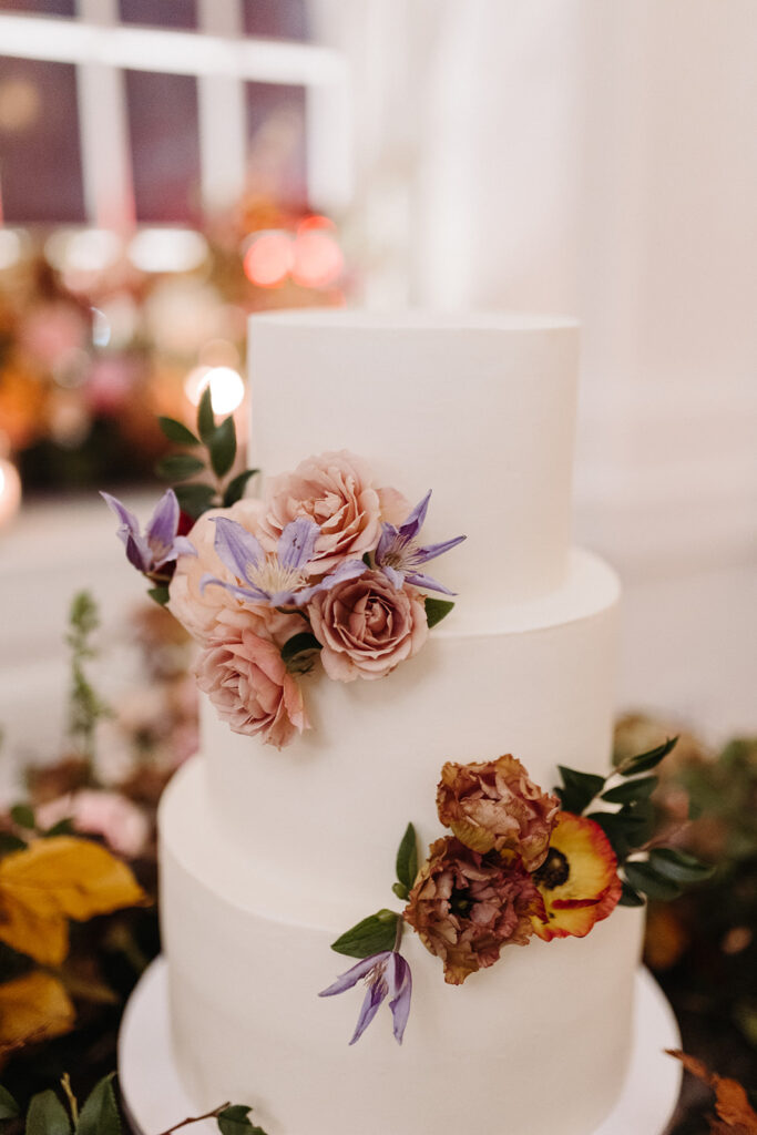 Lush floral meadows surround the wedding cake at this Parisian inspired fall wedding with colors of dusty rose, terra cotta, mauve, copper, and lavender composed of roses, ranunculus, copper beech, clematis, and fall foliage. Fall Wedding in Downtown Nashville. Design by Rosemary & Finch Floral Design in Nashville, TN. 