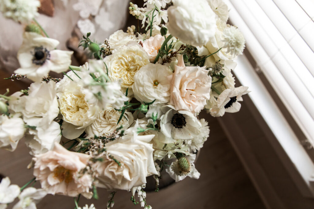 Timeless bridal bouquet with anemones, roses, sweet peas, and ranunculus for fall wedding. Classic floral design with cream, white, and blush flowers. Fall destination wedding outside Nashville, TN. Design by Rosemary & Finch Floral Design. 