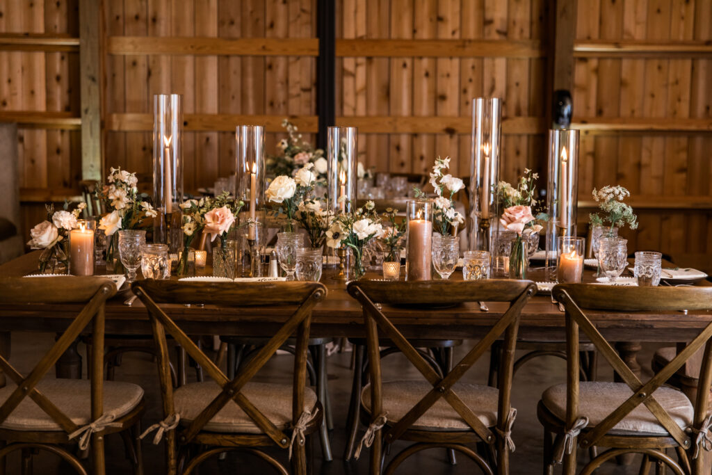 Glamorous fall wedding with timeless floral design and flower colors in white, cream, blush, and black. Bud Vases and candle heavy wedding reception tables create warm ambiance paired with twinkling ceiling lights. Destination wedding in Tennessee countryside. Roses, ranunculus, anemones, and sweet peas. Design by Rosemary & Finch Floral Design in Nashville, TN. 