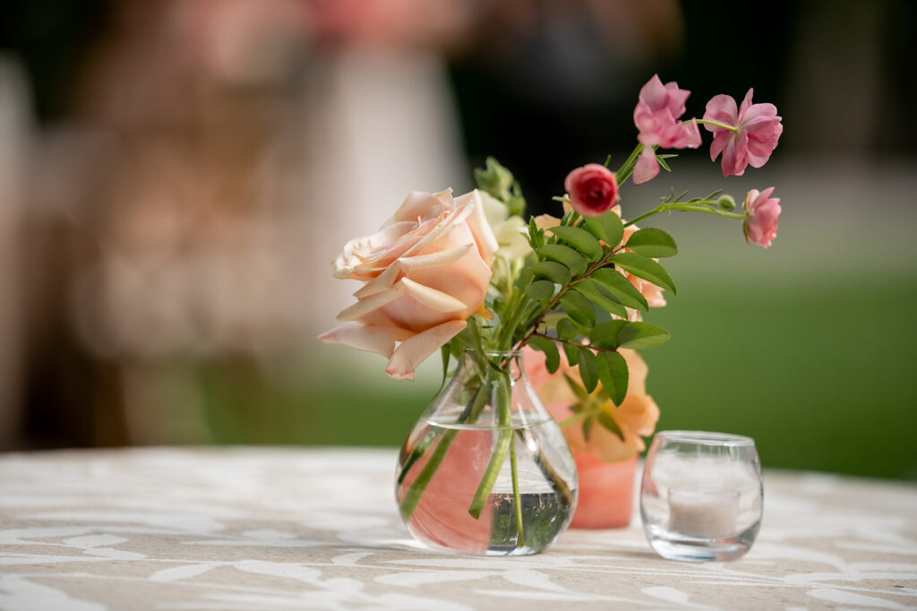 Colorful floral arrangements bring pops of color to this spring outdoor wedding. Vibrant color palettes of pink, peach, blush, and cream flowers bring this wedding reception fun pink florals. Pink bud vases and small arrangements sprinkled around cocktail hour. Destination countryside wedding outside Nashville, TN. Design by Rosemary & Finch Floral Design in Nashville, TN. 