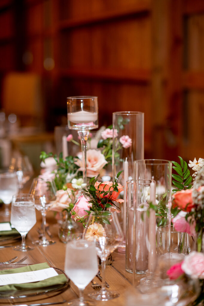 Bud vases on wedding tables bring vibrant color to this spring wedding reception. Fun pink color with flowers such as pink peonies, roses, ranunculus, and tulips decorate this wedding with pops of color. Destination wedding in Tennessee countryside. Design by Rosemary & Finch Floral Design in Nashville, TN.