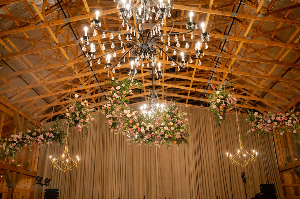 Floral clouds hang over wedding reception dance floor adding vibrant and fun color to spring wedding. Fun pink wedding florals bring exciting color to wedding reception with pink peonies, roses, ranunculus, and tulips. Destination Barbie wedding in Nashville, TN. Design by Rosemary & Finch Floral Design in Nashville, TN.