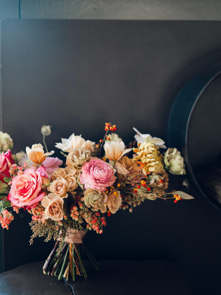 Whimsical bridal bouquet in unique fall tones caramel, dusty rose, peach, tangerine, and copper. Fall floral bouquet with roses, ranunculus, mums, fruiting branches, and clematis. Medium sized bridal bouquet with fall colors. Destination wedding outside Nashville, TN. Design by Rosemary & Finch Floral Design in Nashville, TN. 