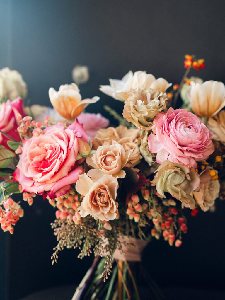 Whimsical bridal bouquet in unique fall tones caramel, dusty rose, peach, tangerine, and copper. Fall floral bouquet with roses, ranunculus, mums, fruiting branches, and clematis. Medium sized bridal bouquet with fall colors. Destination wedding outside Nashville, TN. Design by Rosemary & Finch Floral Design in Nashville, TN. 