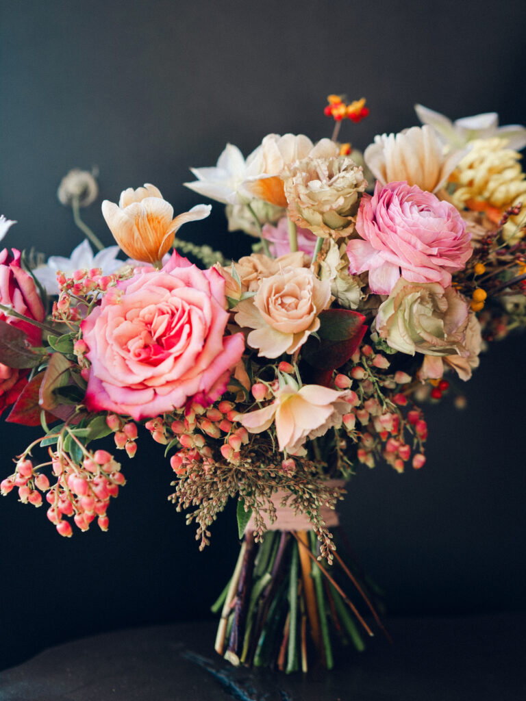 Whimsical bridal bouquet in unique fall tones caramel, dusty rose, peach, tangerine, and copper. Fall floral bouquet with roses, ranunculus, mums, fruiting branches, and clematis. Medium sized bridal bouquet with fall colors. Destination wedding outside Nashville, TN. Design by Rosemary & Finch Floral Design in Nashville, TN. 