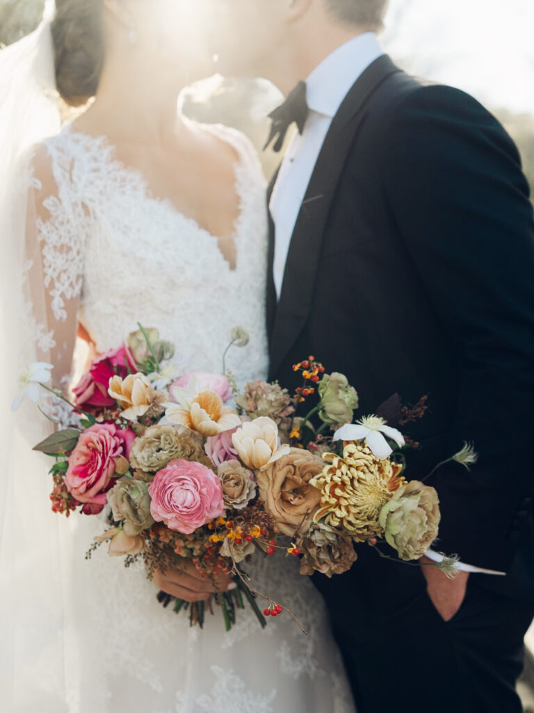 Whimsical bridal bouquet in unique fall tones caramel, dusty rose, peach, tangerine, and copper. Fall floral bouquet with roses, ranunculus, mums, fruiting branches, and clematis. Medium sized bridal bouquet with fall colors. Destination wedding outside Nashville, TN. Design by Rosemary & Finch Floral Design in Nashville, TN. 