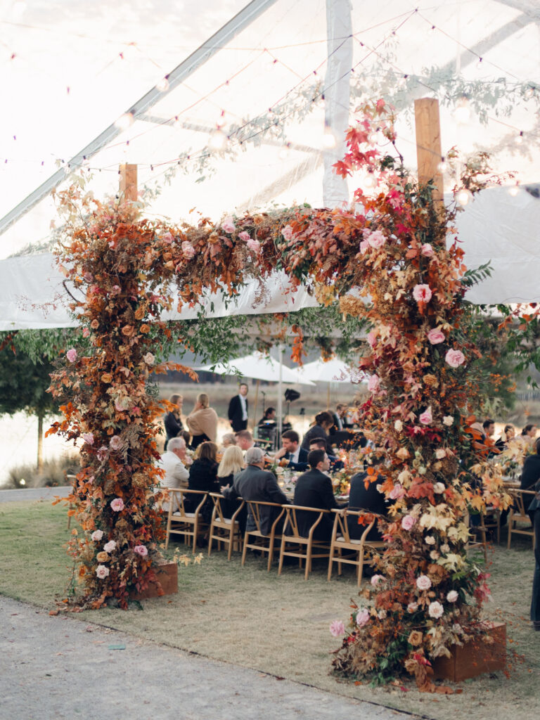 Tent entrance installation for fall wedding at Southall Farm & Inn. Lush floral install makes large impact in blush, tangerine, caramel, and mustard yellow flower colors. Large fall branches and roses make a statement for this wedding reception tent entrance. Destination floral design wedding outside Nashville, TN. Design by Rosemary & Finch Floral Design in Nashville, TN.