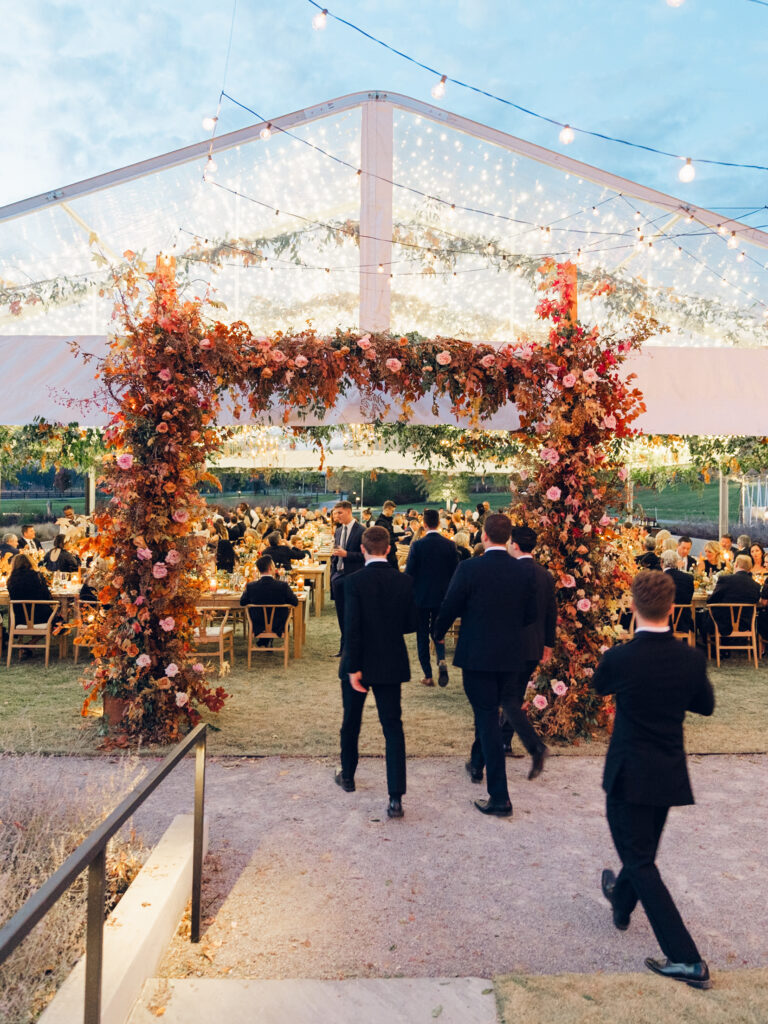 Tent entrance installation for fall wedding at Southall Farm & Inn. Lush floral install makes large impact in blush, tangerine, caramel, and mustard yellow flower colors. Large fall branches and roses make a statement for this wedding reception tent entrance. Destination floral design wedding outside Nashville, TN. Design by Rosemary & Finch Floral Design in Nashville, TN.