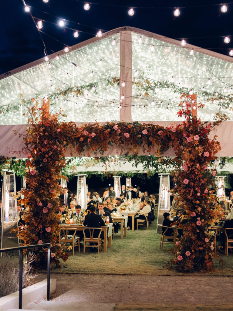 Tent entrance installation for fall wedding at Southall Farm & Inn. Lush floral install makes large impact in blush, tangerine, caramel, and mustard yellow flower colors. Large fall branches and roses make a statement for this wedding reception tent entrance. Destination floral design wedding outside Nashville, TN. Design by Rosemary & Finch Floral Design in Nashville, TN.