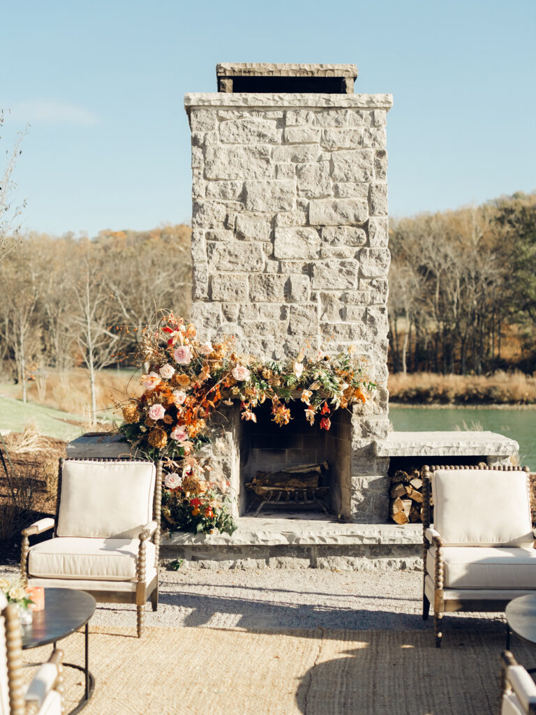 Fireplace floral moment for fall wedding reception at Southall Farm & Inn. Lush floral moment on fireplace in unique floral palette caramel, honey, dusty rose, peach, copper, and burgundy. Fall foliage and roses decorate this cocktail hour lounge area. Destination wedding outside Nashville, TN. Design by Rosemary & Finch Floral Design in Nashville, TN. 