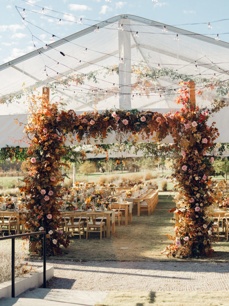 Tent entrance installation for fall wedding at Southall Farm & Inn. Lush floral install makes large impact in blush, tangerine, caramel, and mustard yellow flower colors. Large fall branches and roses make a statement for this wedding reception tent entrance. Destination floral design wedding outside Nashville, TN. Design by Rosemary & Finch Floral Design in Nashville, TN.