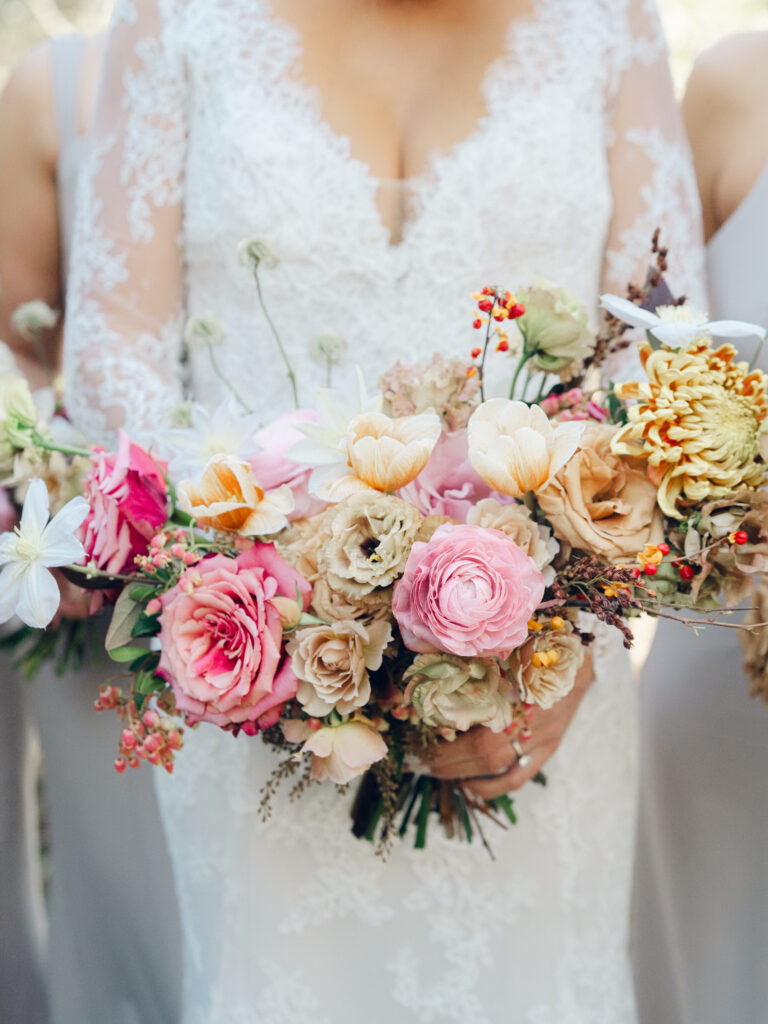 Whimsical bridal bouquet in unique fall tones caramel, dusty rose, peach, tangerine, and copper. Fall floral bouquet with roses, ranunculus, mums, fruiting branches, and clematis. Medium sized bridal bouquet with fall colors. Destination wedding outside Nashville, TN. Design by Rosemary & Finch Floral Design in Nashville, TN. 