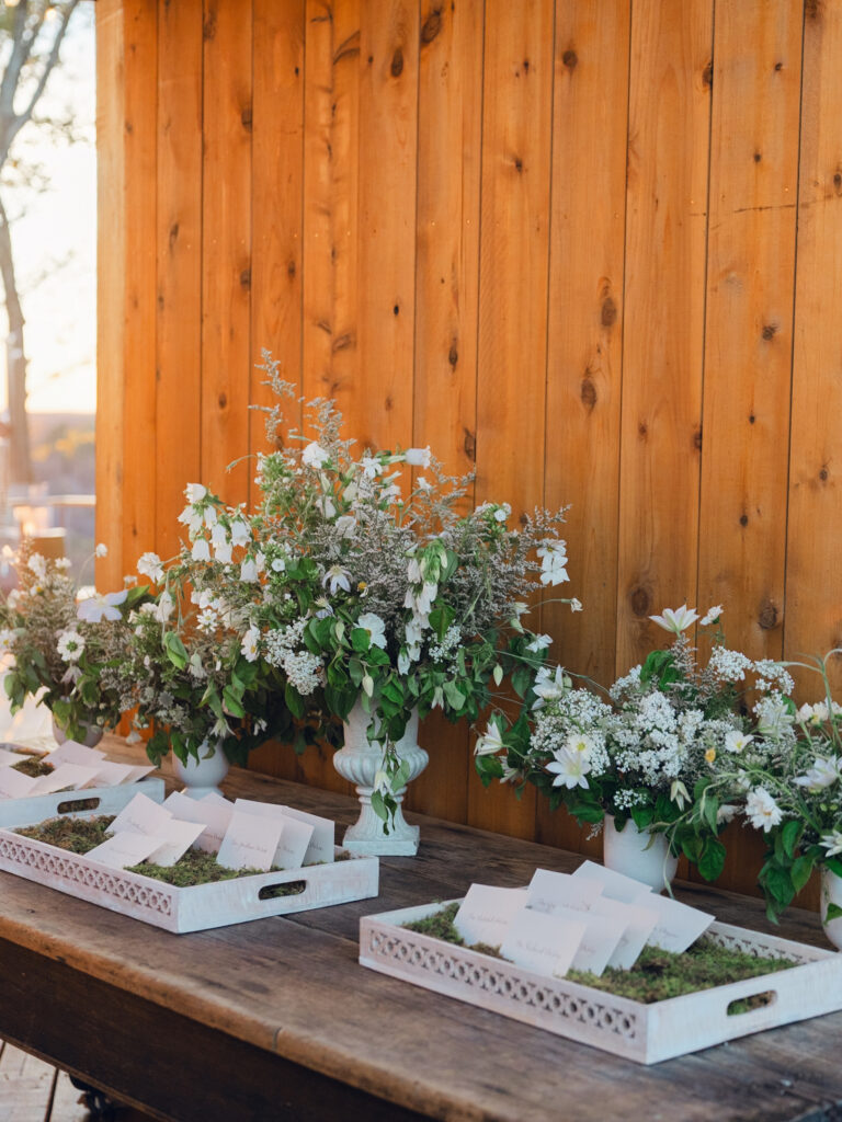 Rehearsal dinner on hilltop of Tennessee countryside resort Southall Farm & Inn. Classic whimsical white florals decorate this dinner reception with timeless garden-inspired floral design. Escort cards for wedding reception styled in moss trays. Destination wedding outside Nashville, TN. Design by Rosemary & Finch Floral Design in Nashville, TN. 