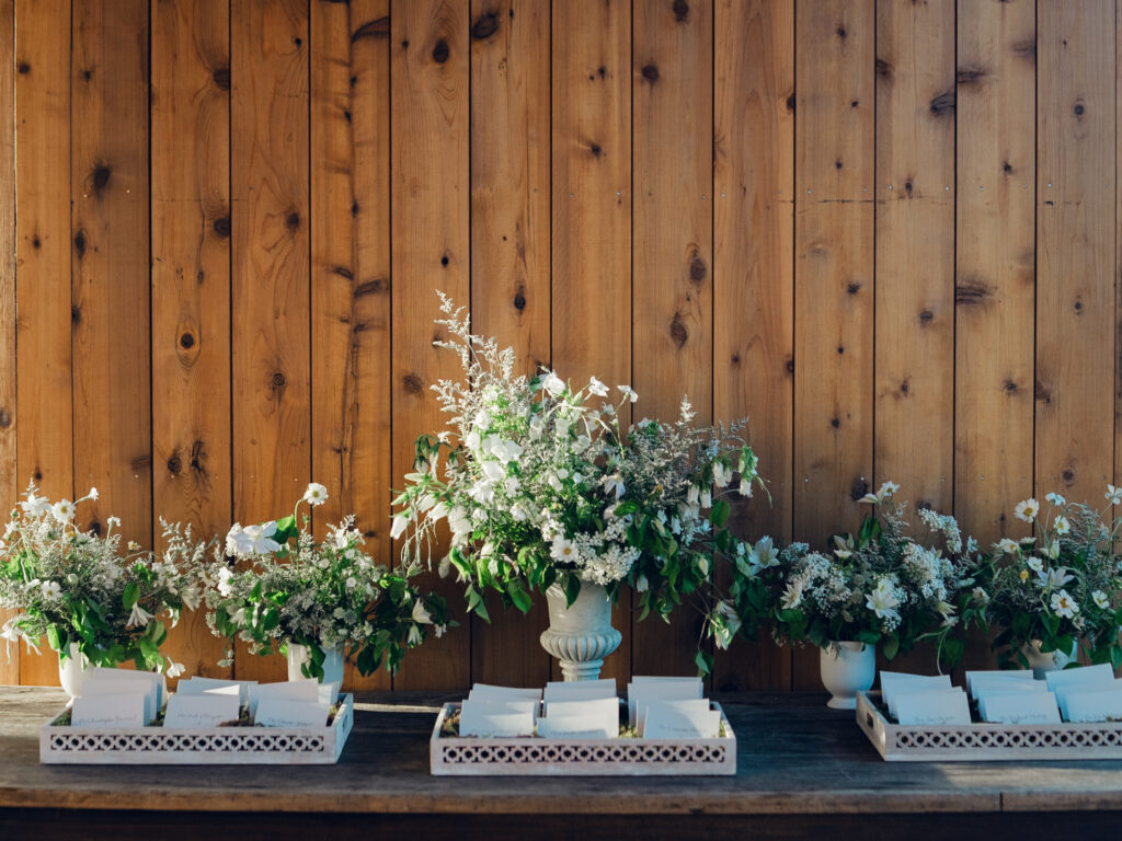 Rehearsal dinner on hilltop of Tennessee countryside resort Southall Farm & Inn. Classic whimsical white florals decorate this dinner reception with timeless garden-inspired floral design. Escort cards for wedding reception styled in moss trays. Destination wedding outside Nashville, TN. Design by Rosemary & Finch Floral Design in Nashville, TN. 